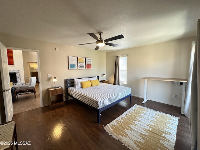 bedroom with ceiling fan, a textured ceiling, baseboards, and wood finished floors