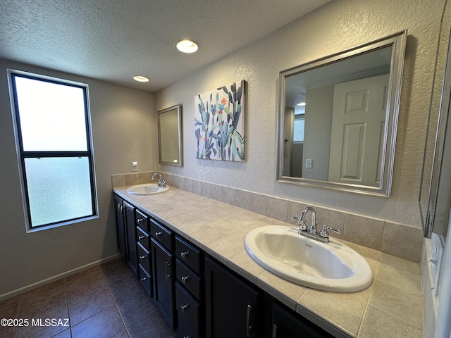 full bath with a textured ceiling, a sink, and a textured wall