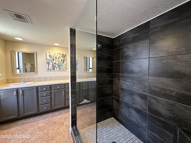 full bath featuring tile patterned flooring, visible vents, walk in shower, and vanity