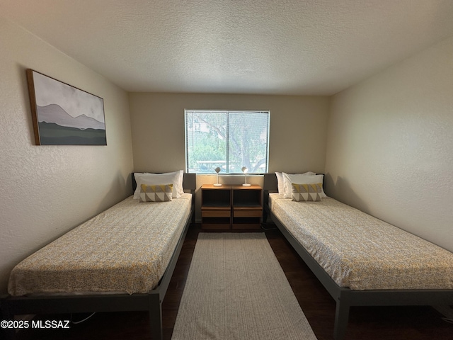 bedroom featuring dark wood-style floors, a textured wall, and a textured ceiling