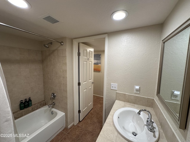 full bathroom with a textured wall, bathtub / shower combination, tile patterned flooring, a sink, and visible vents