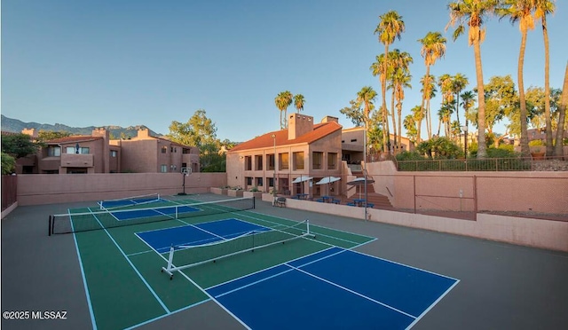 view of tennis court with a residential view and fence