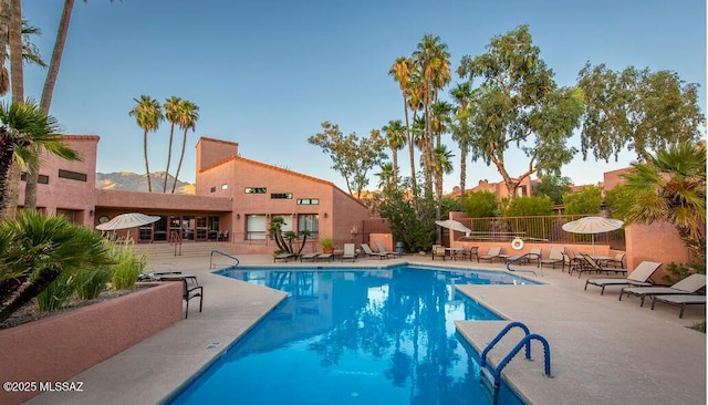 community pool with a patio area and fence