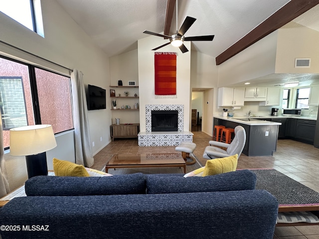 living area with light tile patterned floors, high vaulted ceiling, beam ceiling, and a tile fireplace