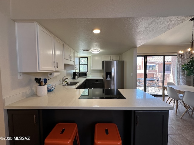 kitchen with white cabinets, appliances with stainless steel finishes, a peninsula, light countertops, and a sink