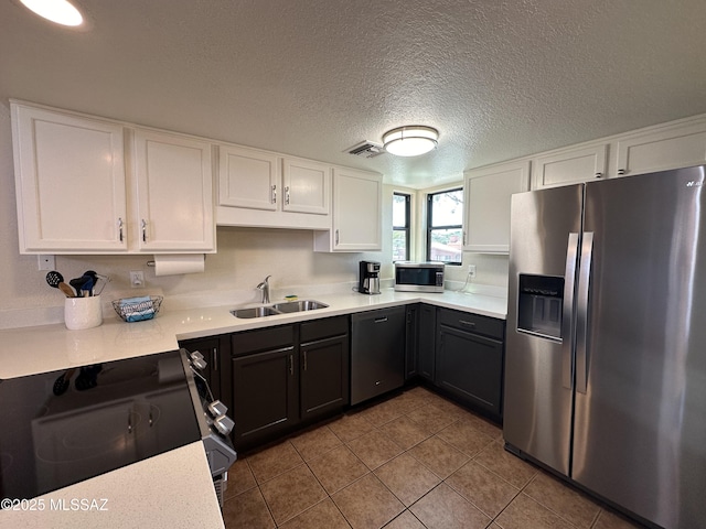 kitchen with stainless steel appliances, light countertops, visible vents, white cabinets, and a sink