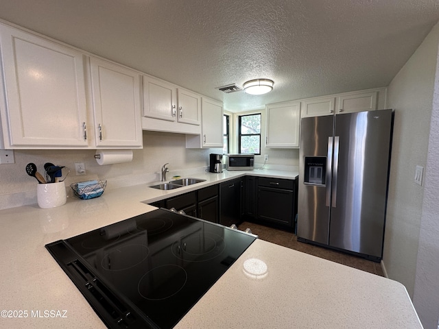 kitchen with appliances with stainless steel finishes, light countertops, white cabinetry, and a sink