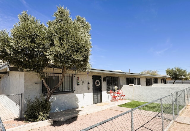 view of front of house featuring stucco siding and fence private yard