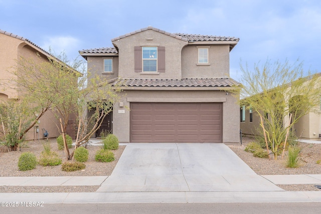 mediterranean / spanish-style home with concrete driveway, an attached garage, a tiled roof, and stucco siding