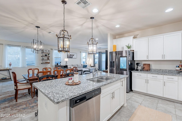 kitchen featuring a center island with sink, stainless steel appliances, visible vents, white cabinets, and a sink