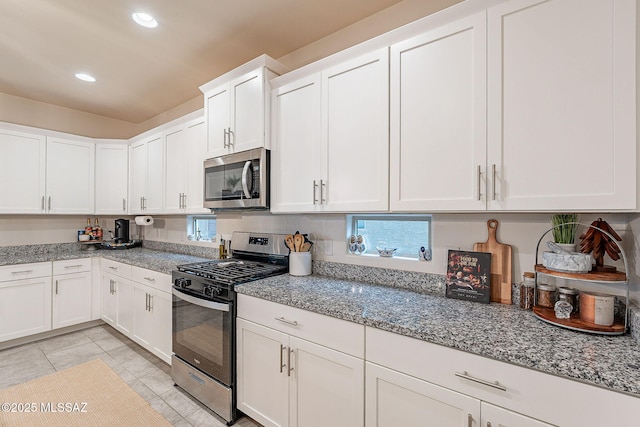 kitchen with stainless steel appliances, recessed lighting, light stone countertops, and white cabinets