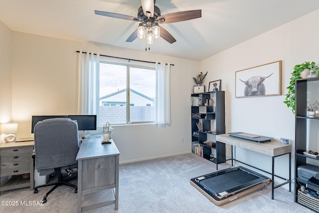 carpeted office space with a ceiling fan and baseboards