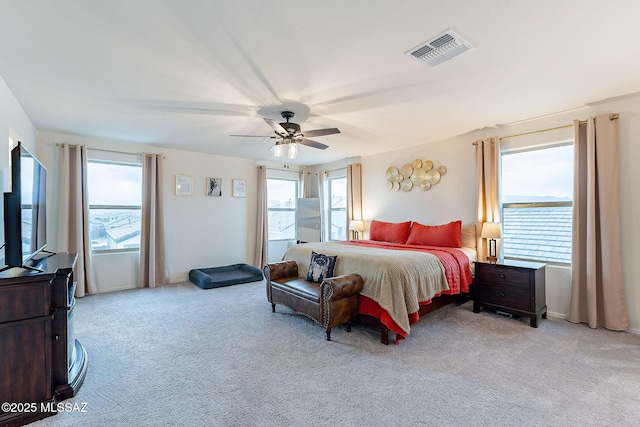 bedroom featuring a ceiling fan, visible vents, and light colored carpet