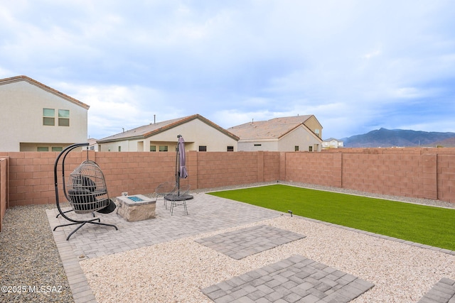 view of patio / terrace featuring a fenced backyard, a fire pit, and a mountain view