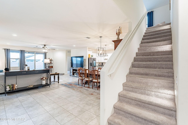 staircase featuring tile patterned flooring, visible vents, recessed lighting, and ceiling fan with notable chandelier