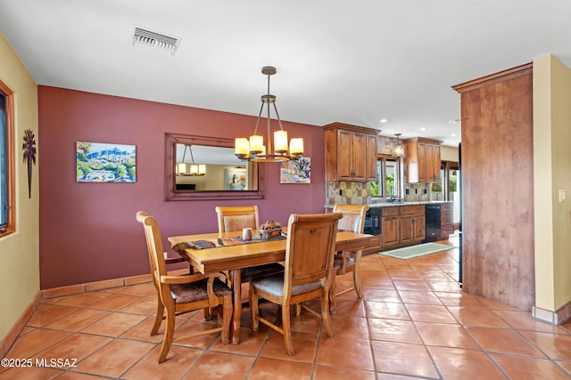 dining room with light tile patterned floors, a notable chandelier, visible vents, and baseboards