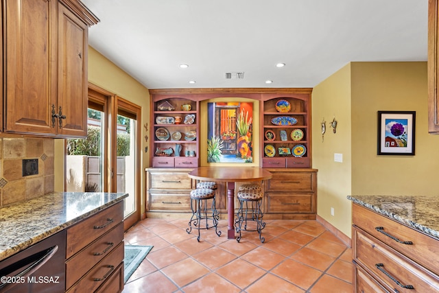 kitchen with tasteful backsplash, light stone countertops, visible vents, and open shelves