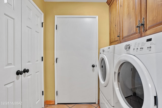 clothes washing area featuring cabinet space, washer and clothes dryer, and light tile patterned floors