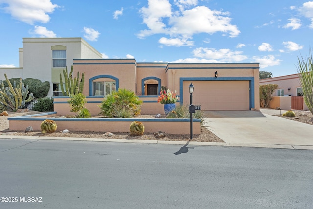 view of front of home with driveway, a fenced front yard, a garage, and stucco siding