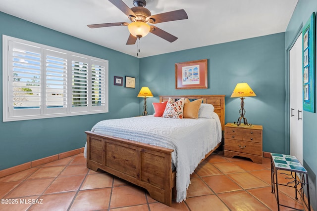 bedroom with ceiling fan, tile patterned floors, and baseboards