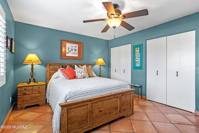 bedroom with light tile patterned floors, a ceiling fan, and multiple closets