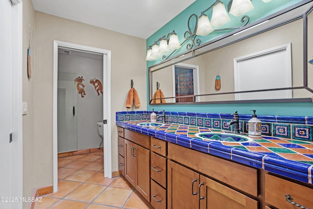 full bathroom with double vanity, a sink, toilet, and tile patterned floors