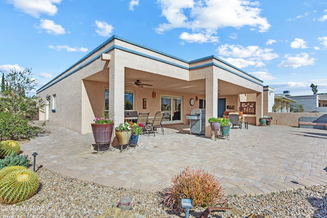 rear view of house featuring outdoor dining space, a patio area, ceiling fan, and stucco siding