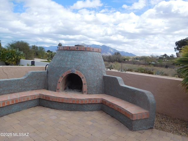 view of patio / terrace with an outdoor brick fireplace and a mountain view