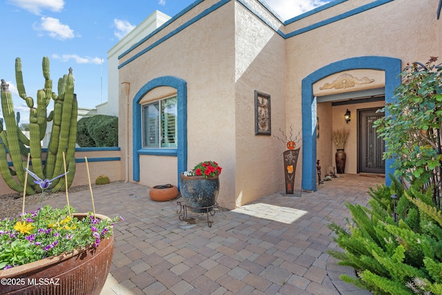 entrance to property with a patio and stucco siding