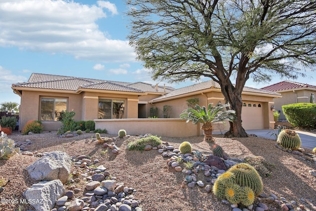 view of front of house featuring a tiled roof, stucco siding, a garage, and fence