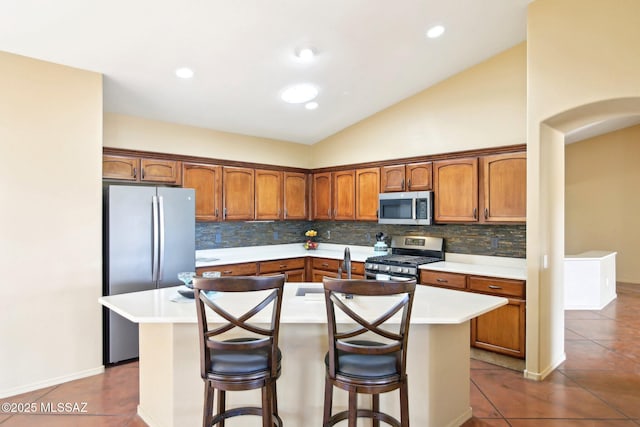 kitchen featuring tile patterned floors, stainless steel appliances, a kitchen island, and light countertops