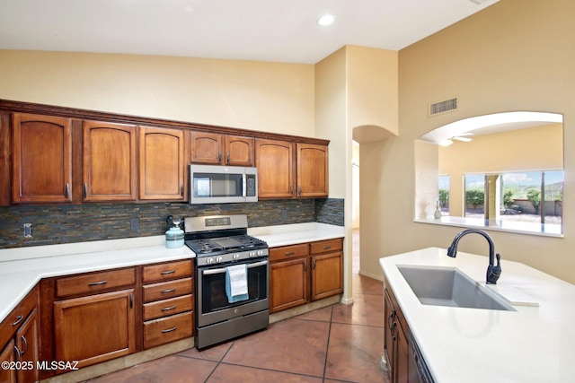 kitchen featuring visible vents, light countertops, decorative backsplash, stainless steel appliances, and a sink