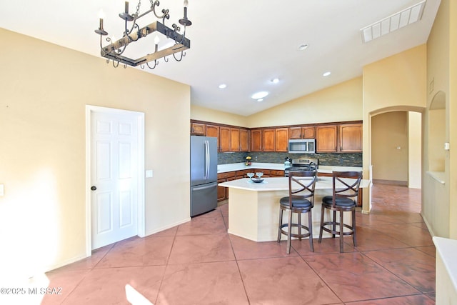 kitchen with light tile patterned floors, visible vents, arched walkways, stainless steel appliances, and backsplash