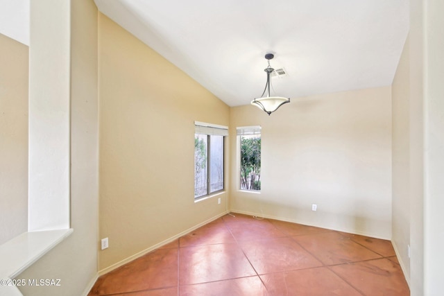 spare room featuring visible vents, baseboards, tile patterned flooring, and vaulted ceiling