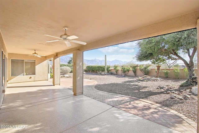 view of patio featuring fence, a ceiling fan, and a mountain view