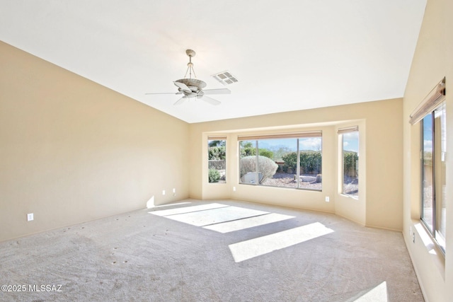 empty room with lofted ceiling, visible vents, carpet floors, and ceiling fan