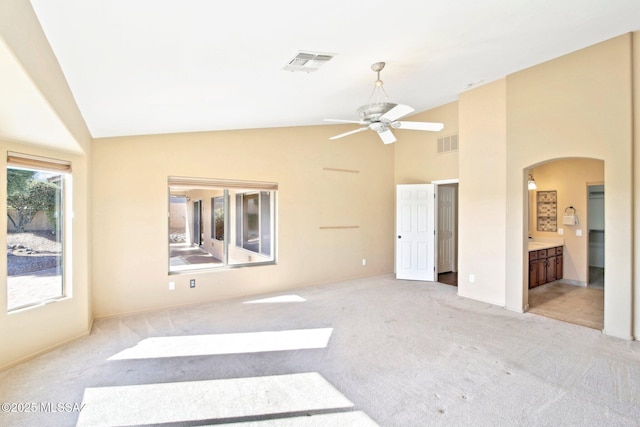 bedroom featuring visible vents, arched walkways, connected bathroom, and carpet flooring