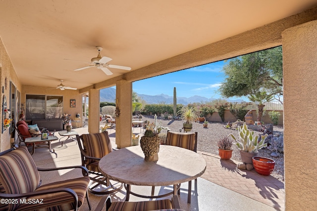 view of patio with ceiling fan, a mountain view, a fenced backyard, and outdoor dining space