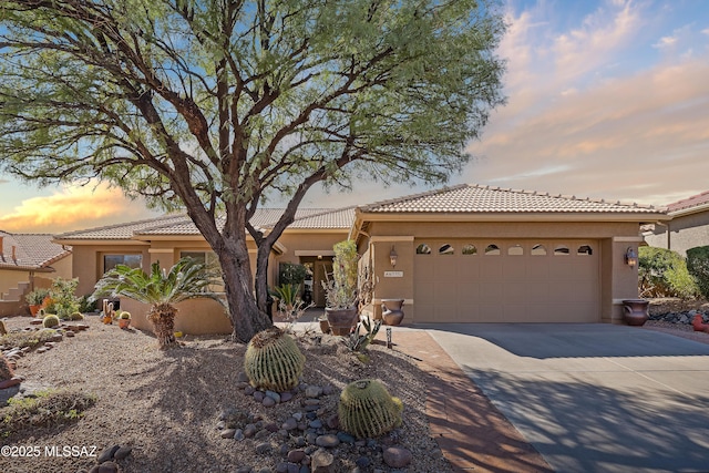 view of front of home featuring a tiled roof, stucco siding, driveway, and a garage