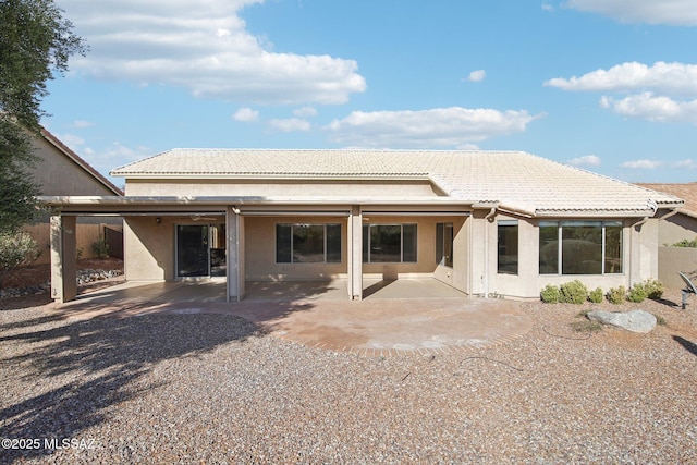 rear view of property with stucco siding, a patio, and a tile roof