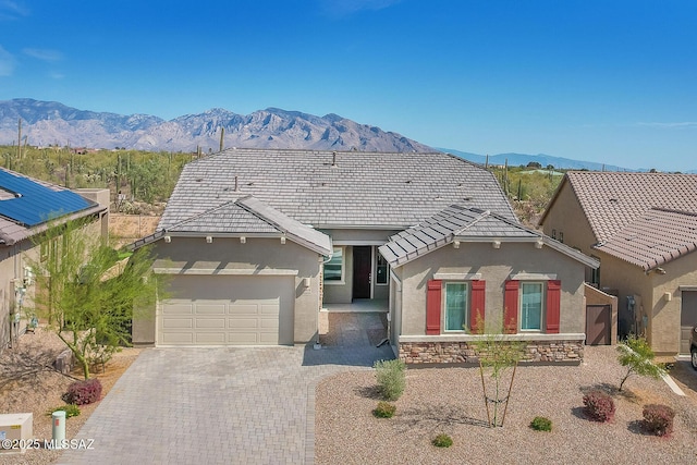 view of front of house with a mountain view, stucco siding, an attached garage, and driveway