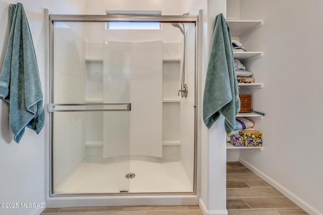 bathroom with a shower stall, baseboards, and wood tiled floor