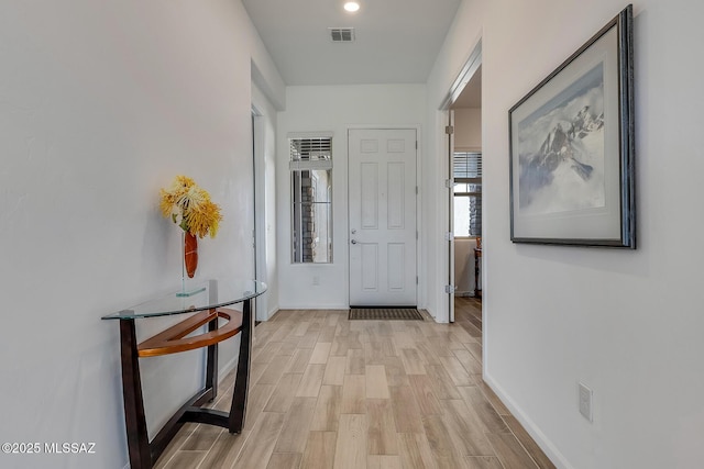 hallway featuring light wood finished floors, visible vents, and baseboards