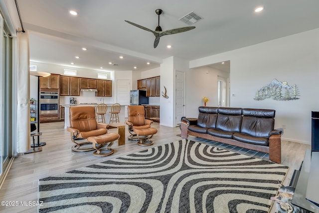 living room with light wood finished floors, visible vents, baseboards, ceiling fan, and recessed lighting