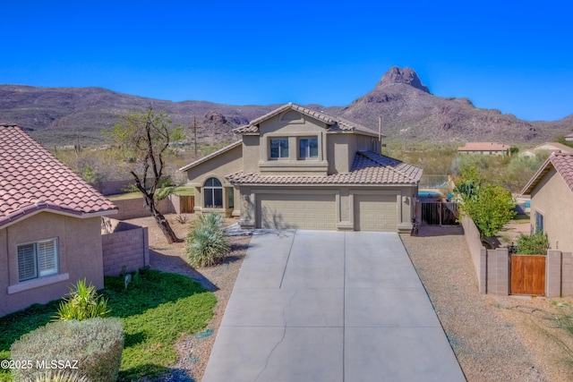 view of front of property featuring stucco siding, a tile roof, fence, a mountain view, and an attached garage