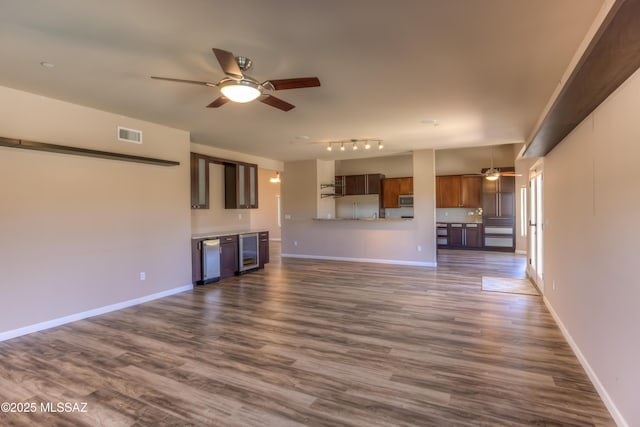 unfurnished living room featuring wine cooler, baseboards, visible vents, and ceiling fan