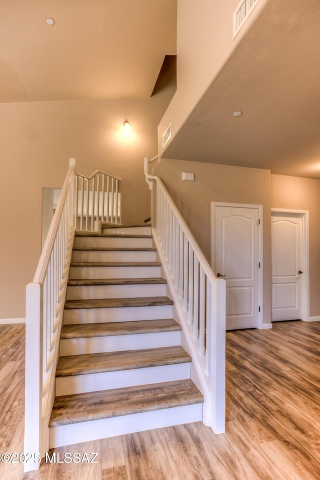 staircase with visible vents, baseboards, and wood finished floors