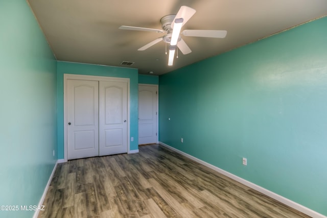 unfurnished bedroom featuring a closet, baseboards, visible vents, and wood finished floors