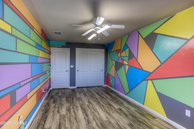 unfurnished bedroom featuring a ceiling fan, wood finished floors, visible vents, and baseboards