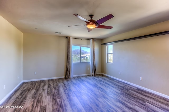 spare room with visible vents, wood finished floors, baseboards, and ceiling fan